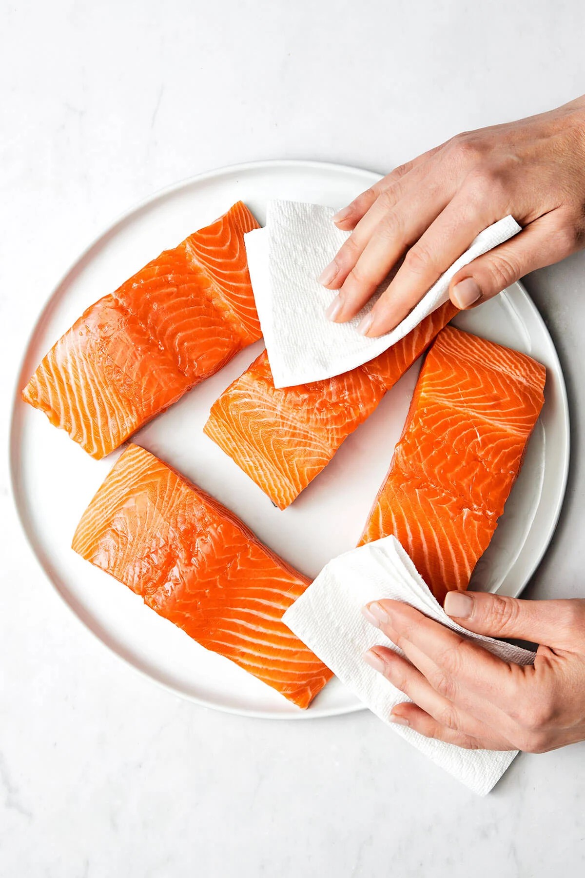Patting salmon dry with a paper towel.