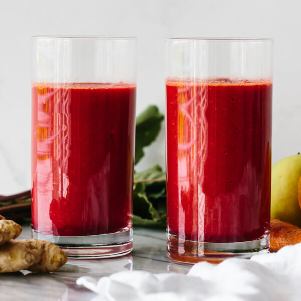 Two glasses of apple carrot beet smoothie next to ingredients.