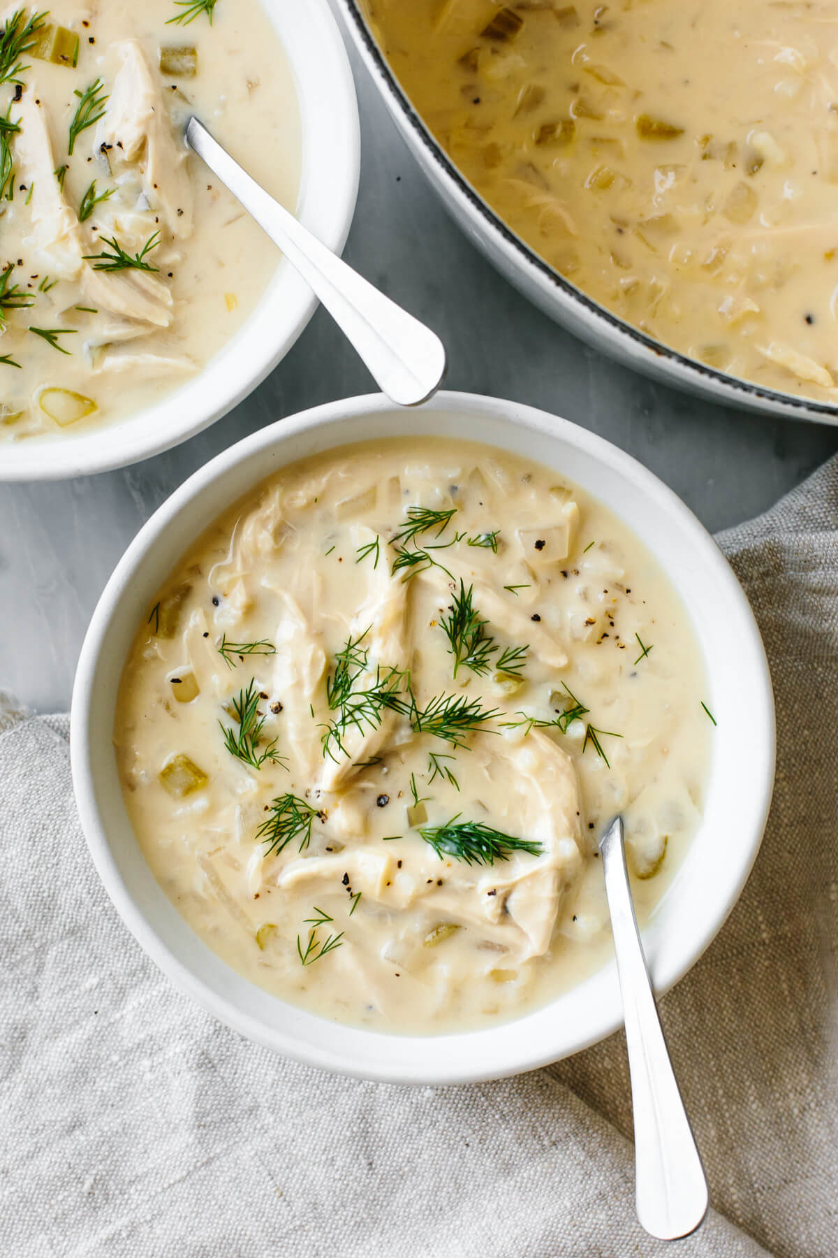 Avgolemono soup in a white bowl with a spoon