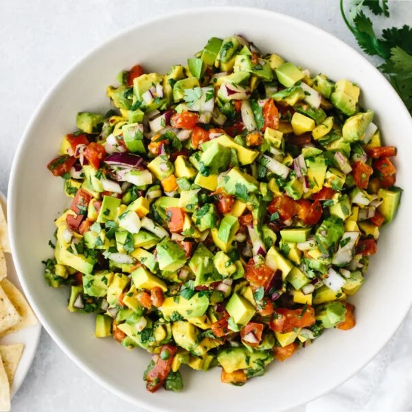 Avocado salsa in a bowl with tortilla chips on the side.