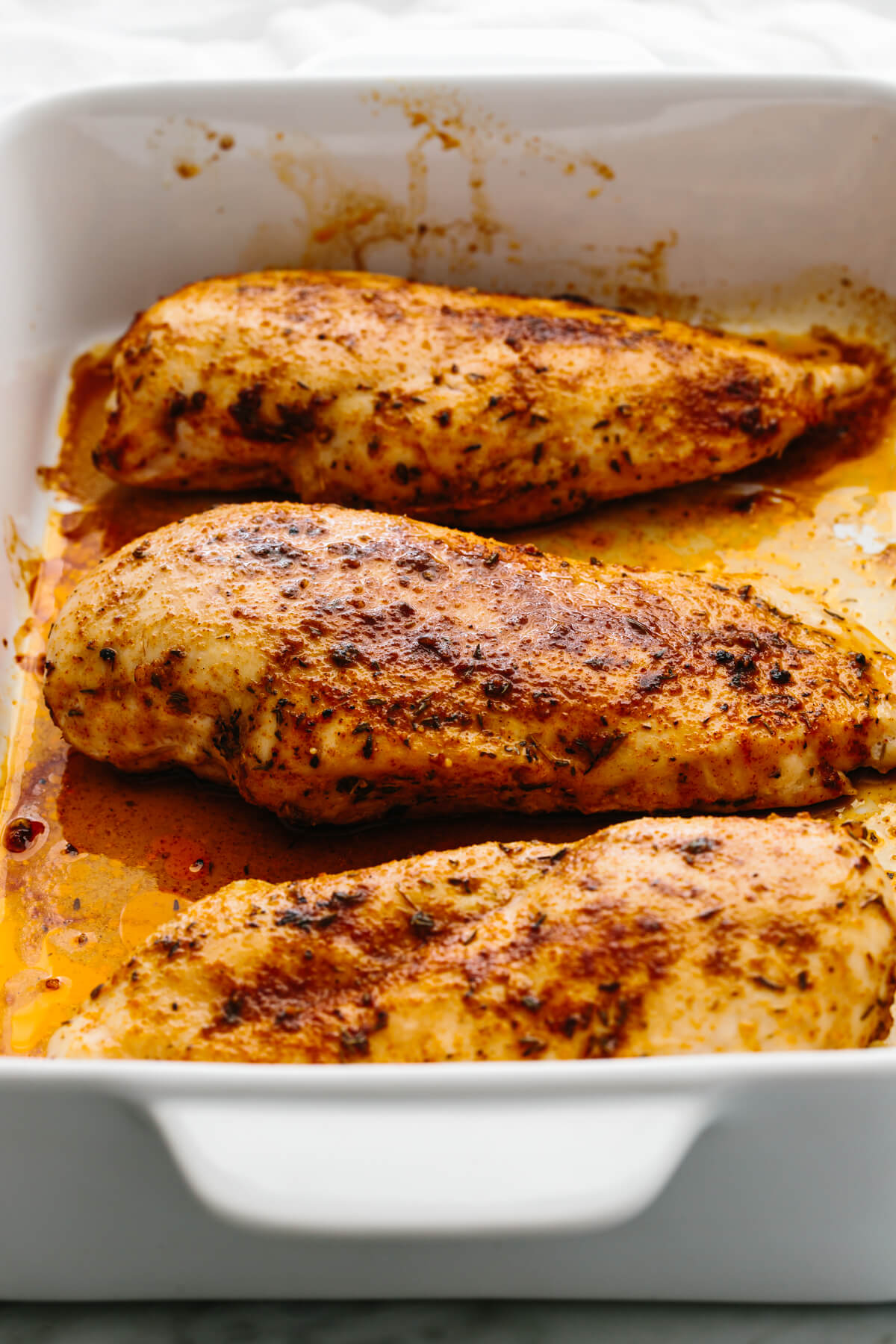 Baked chicken breasts in a pan.