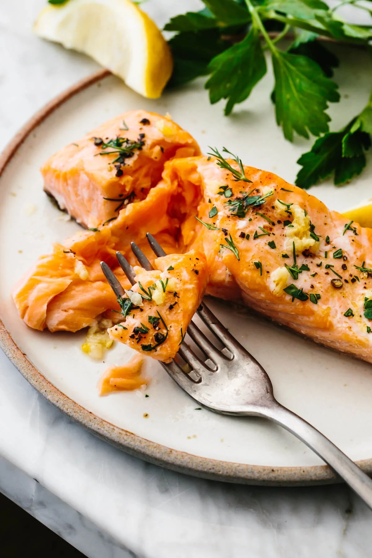 Baked salmon on a plate with a fork and parsley.