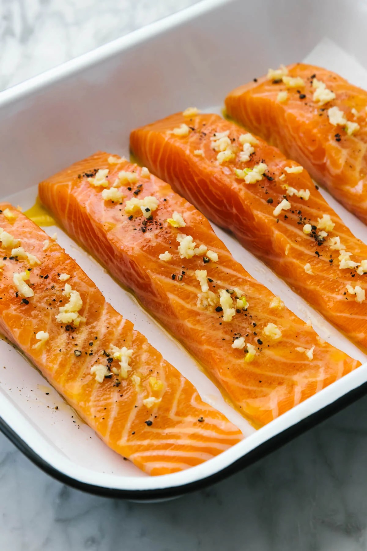 A pan with baked salmon and garlic butter sauce.