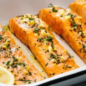 Baked salmon in a white baking dish.