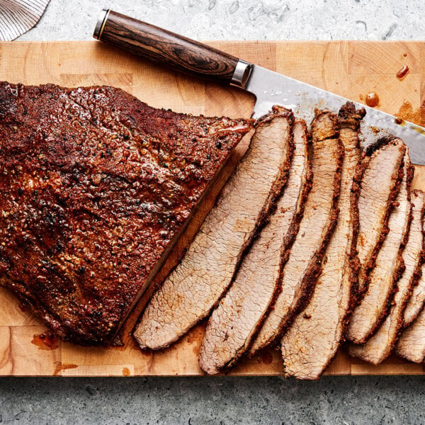 Brisket on a wooden board with a knife.