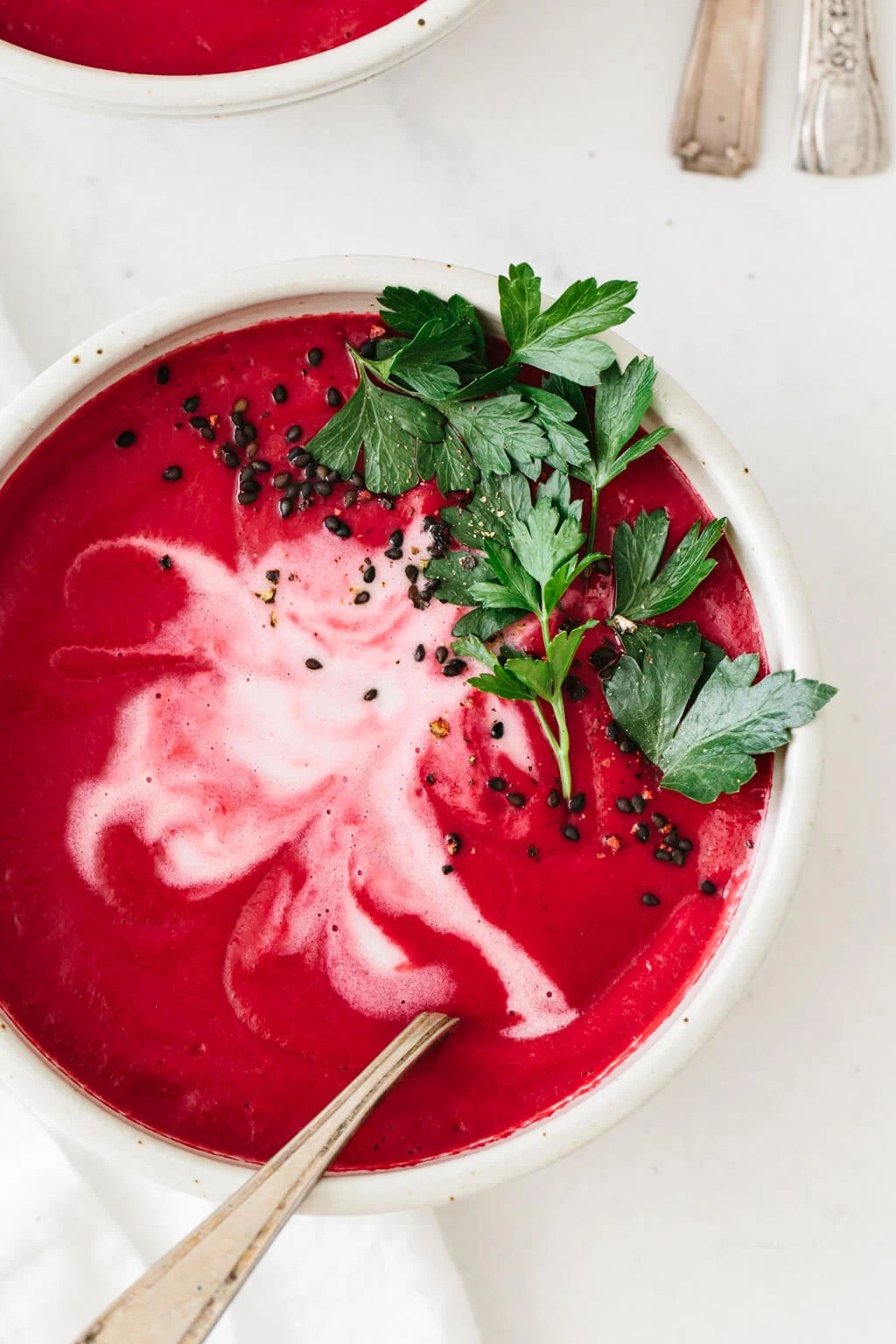 Beet soup garnished with parsley in a bowl.