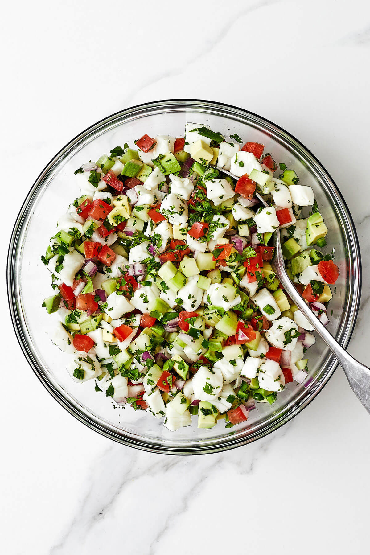 Mixing ceviche in a glass bowl