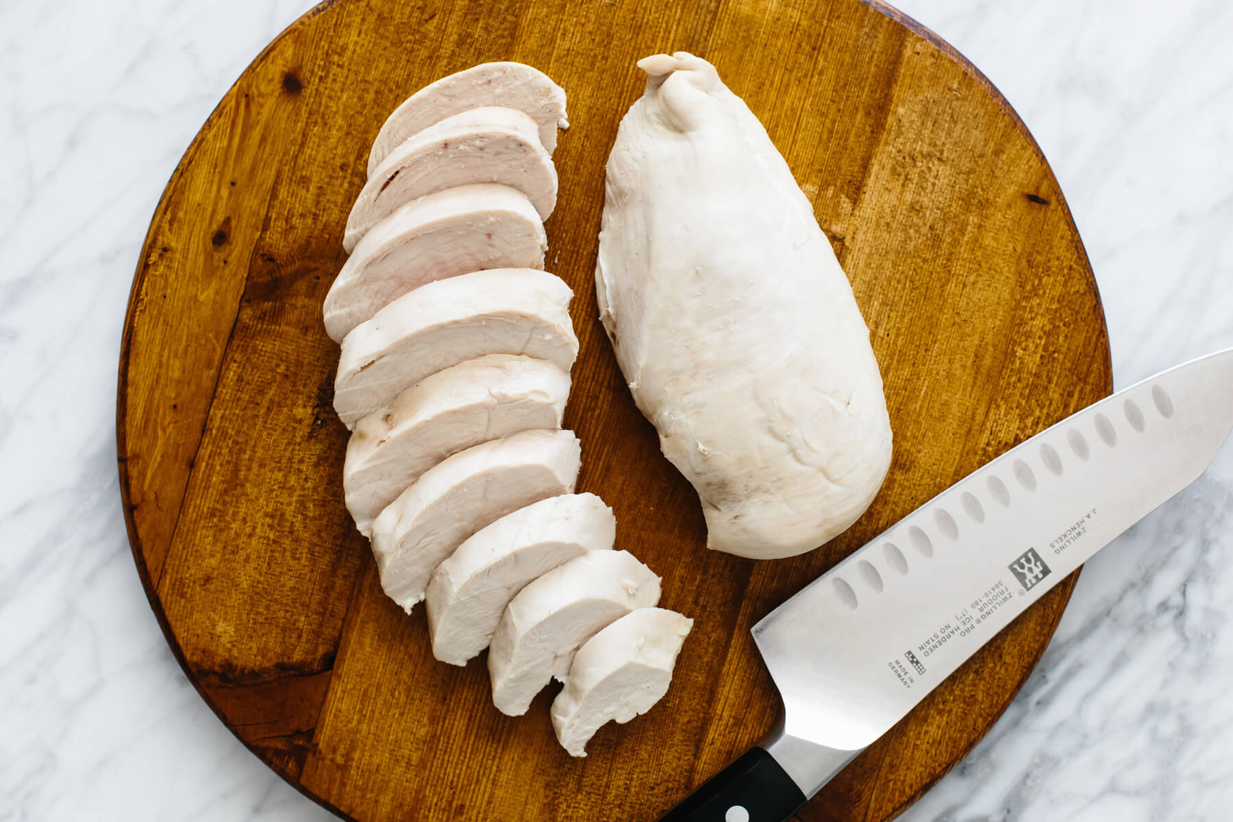 Slicing poached chicken for chicken salad recipe.