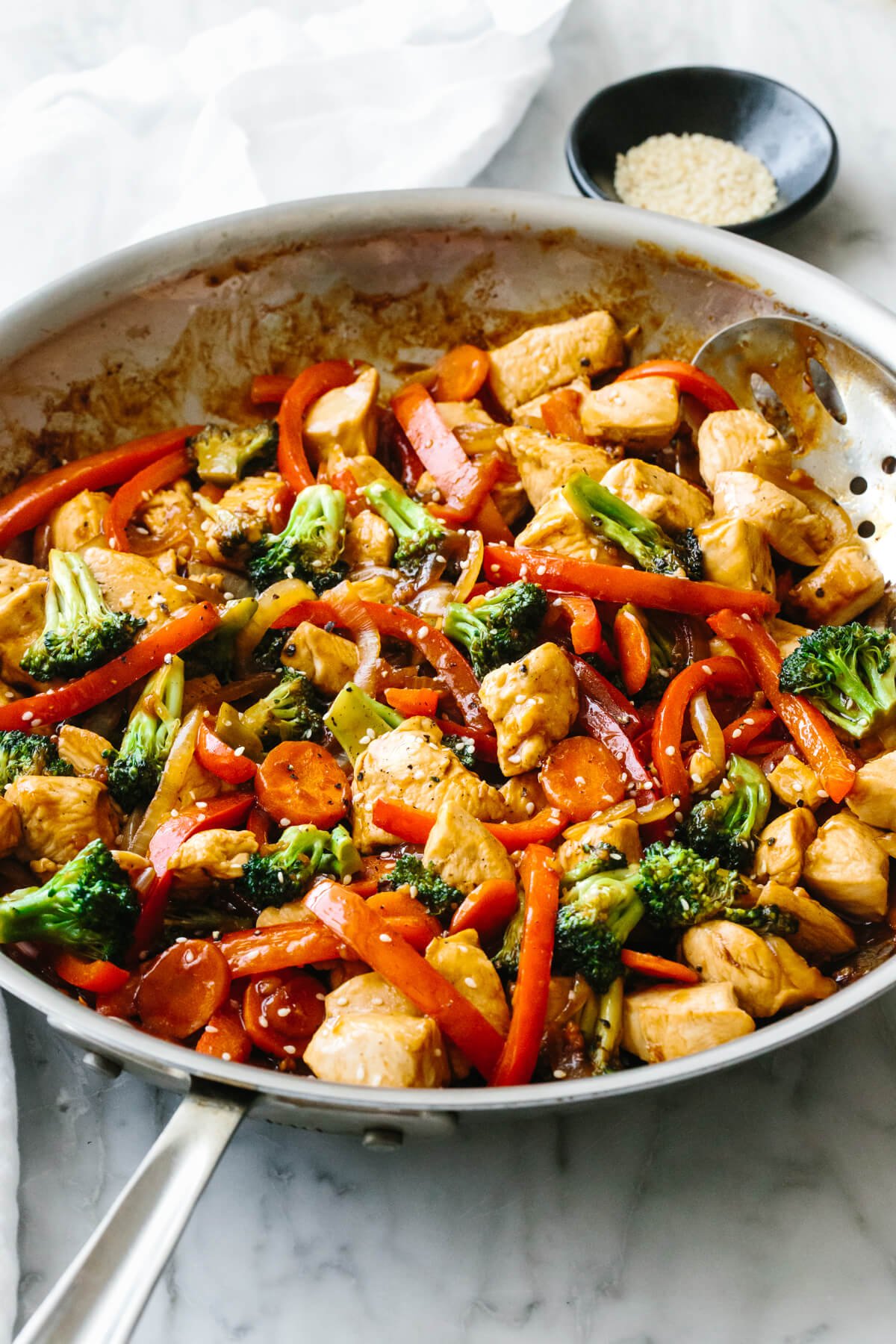 A pan with chicken stir-fry next to a napkin