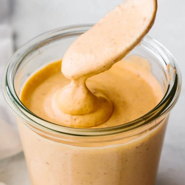 A glass jar of chipotle sauce with a spoon dipping into it.