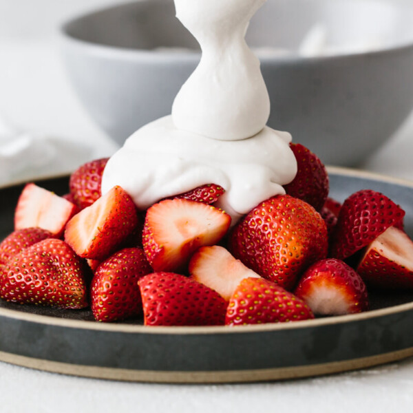 Coconut whipped cream on a plate of strawberries.