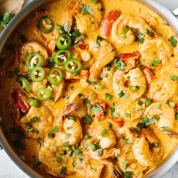 Creamy chipotle shrimp in a saute pan sprinkled with cilantro and peppers.