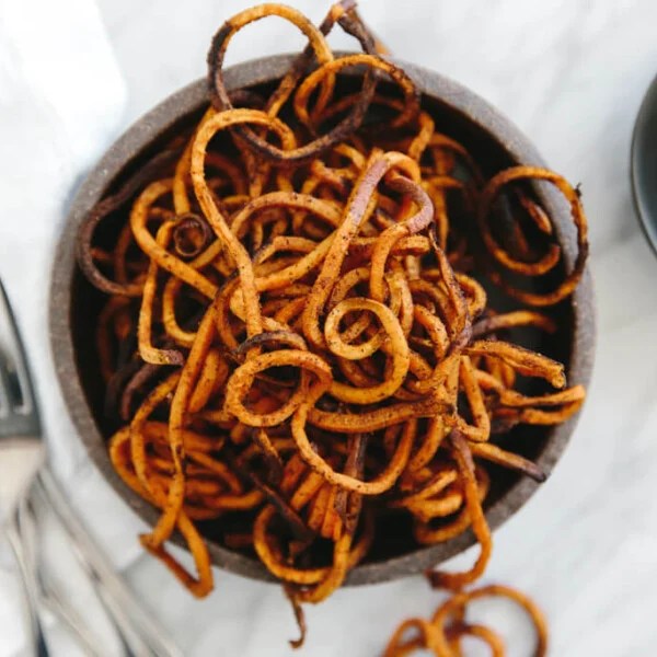 (gluten-free, paleo) Curly sweet potato fries are easily made with a spiralizer. They're seasoned with paprika and garlic powder and baked in the oven until perfectly crispy.