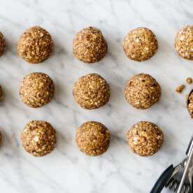 Several energy balls on a counter next to a cookie scoop.