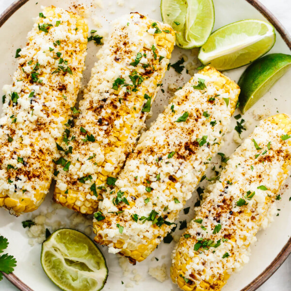 A plate of elote with cheese and lime