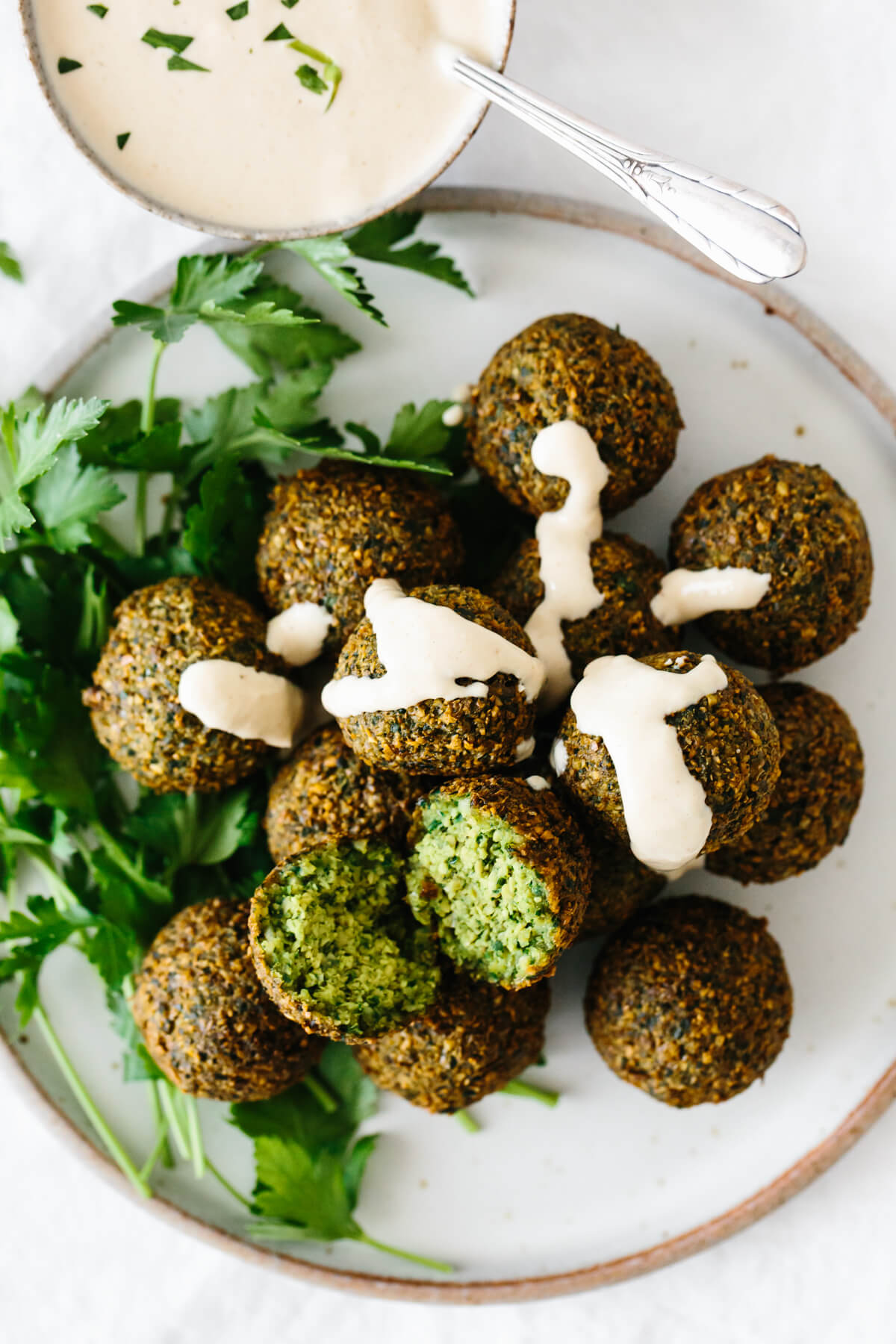 A plate of falafel drizzled with tahini sauce.