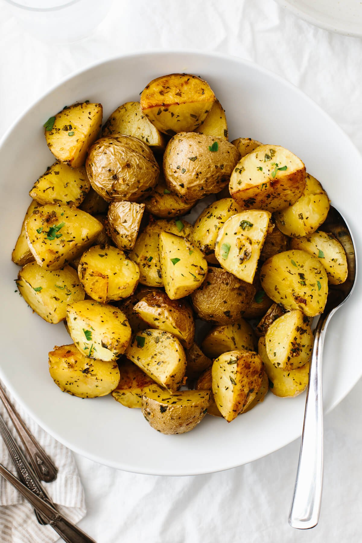 Garlic herb roasted potatoes in a white serving bowl.