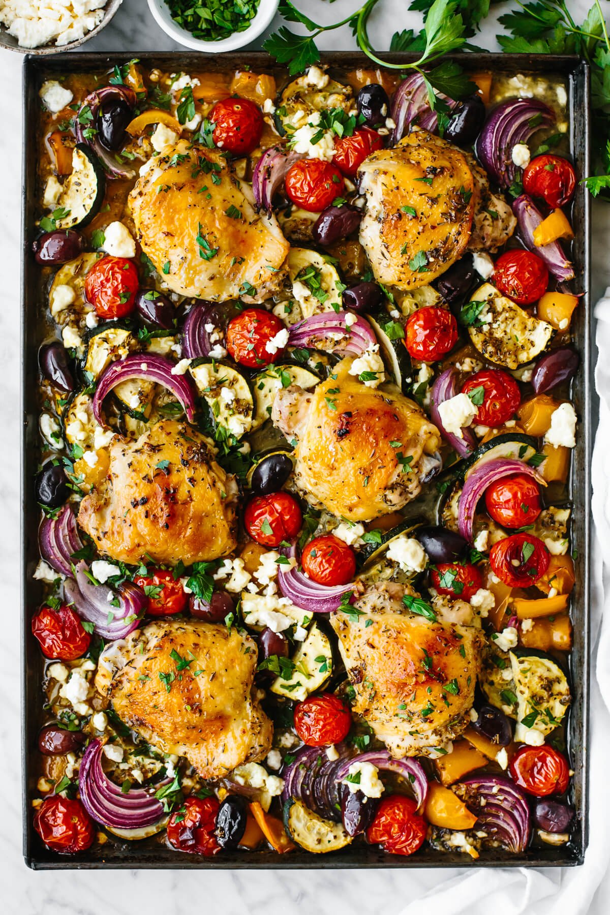 Cooked chicken and Mediterranean vegetables on a sheet pan.