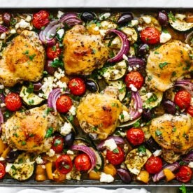 A sheet pan of chicken thighs and Mediterranean vegetables.