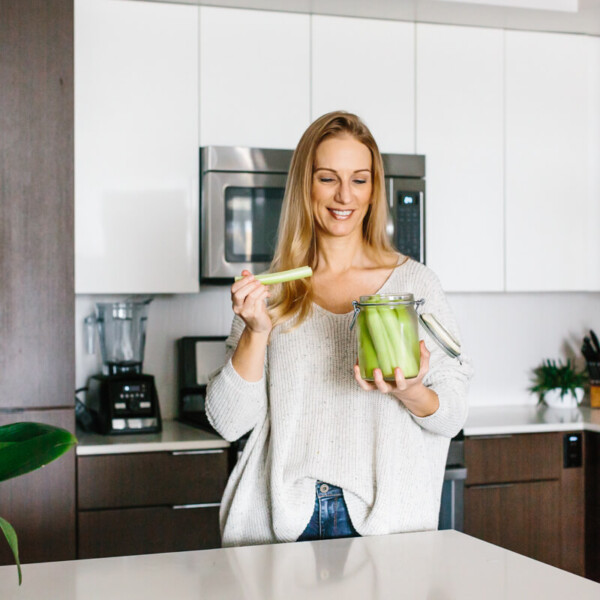 Girl standing in kitchen eating celery sticks