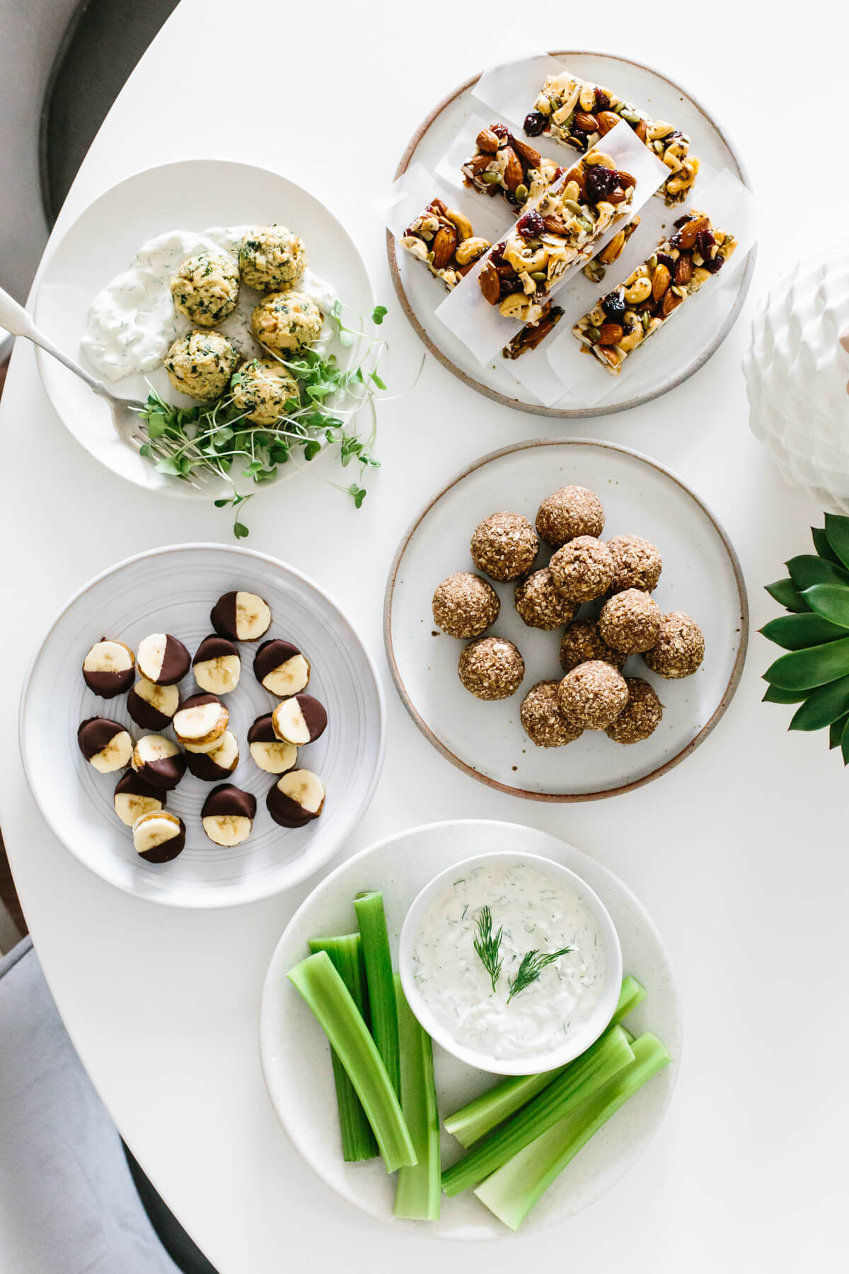 Several healthy snacks and ideas on separate plates on a table.