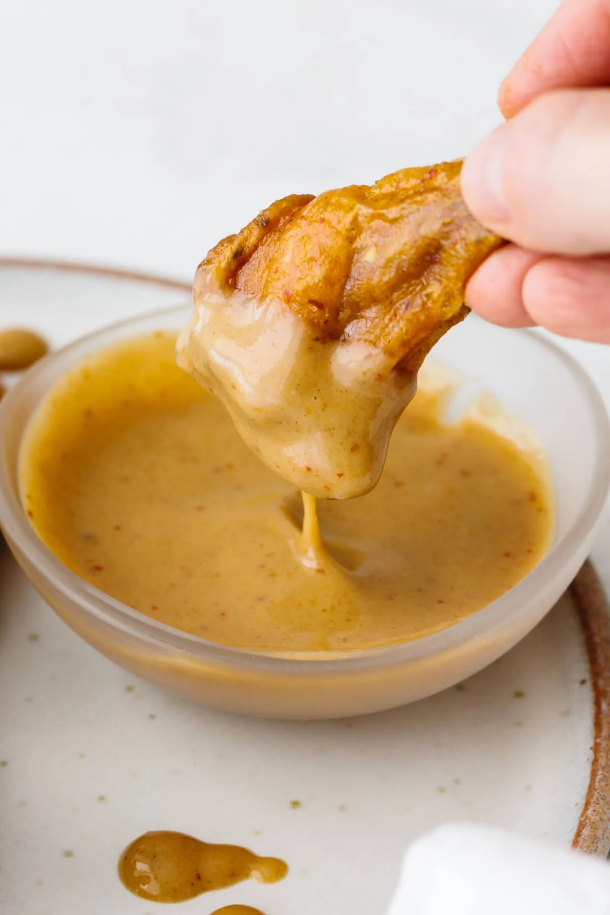 Honey mustard chicken wing dipping into honey mustard sauce.