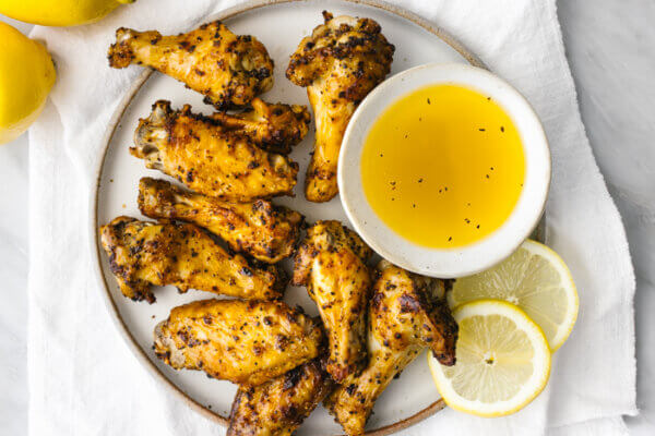Lemon pepper air fryer chicken wings on a plate with lemon slices