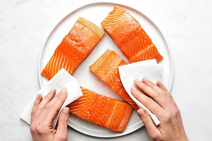 Patting salmon with a paper towel.