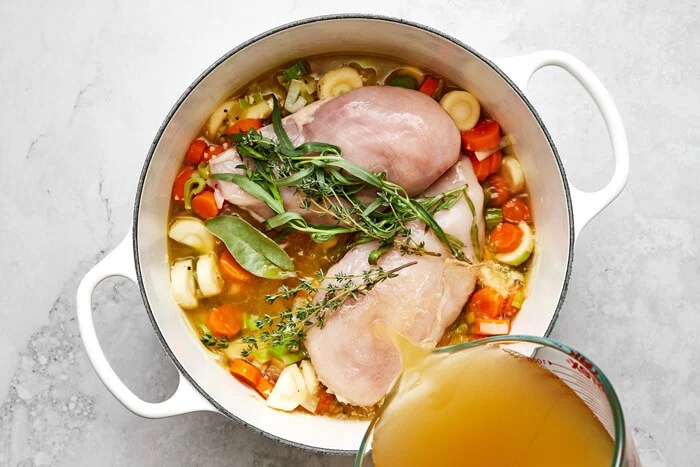 Cooking chicken breast and vegetables in a pot.