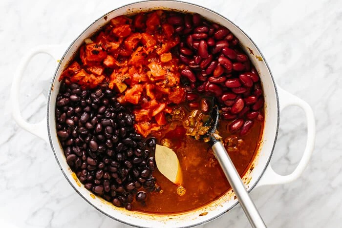 Adding beans to a pot to make chili.