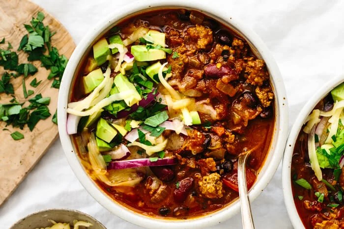 A bowl of beef chili with toppings.