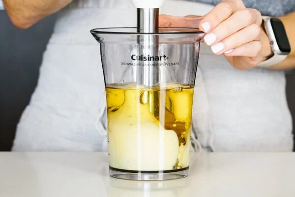 Blending homemade mayonnaise in a jar with a stick blender.