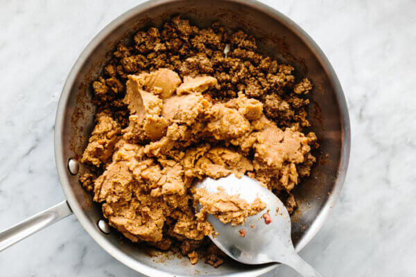 Cooking meat and refried beans in a pan for nachos