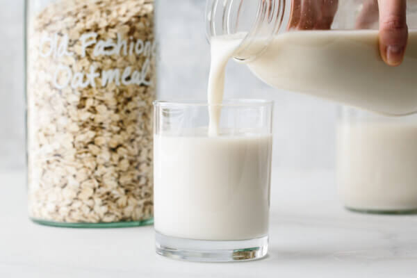 Pouring a glass of oat milk.