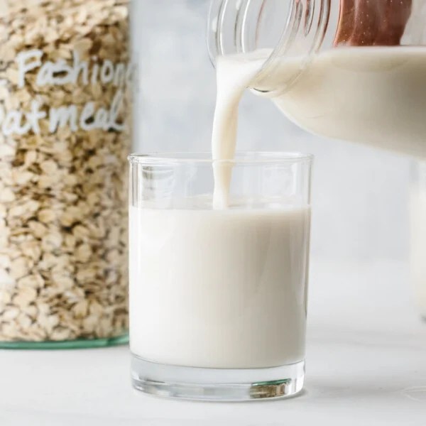 Pouring a glass of oat milk.