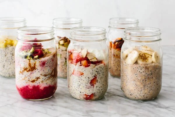 Different flavored overnight oats in jars on table.