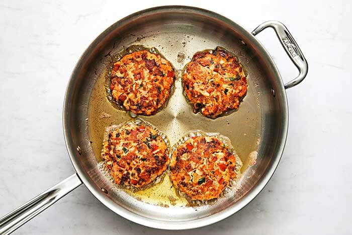 Cooked salmon patties in a pan.