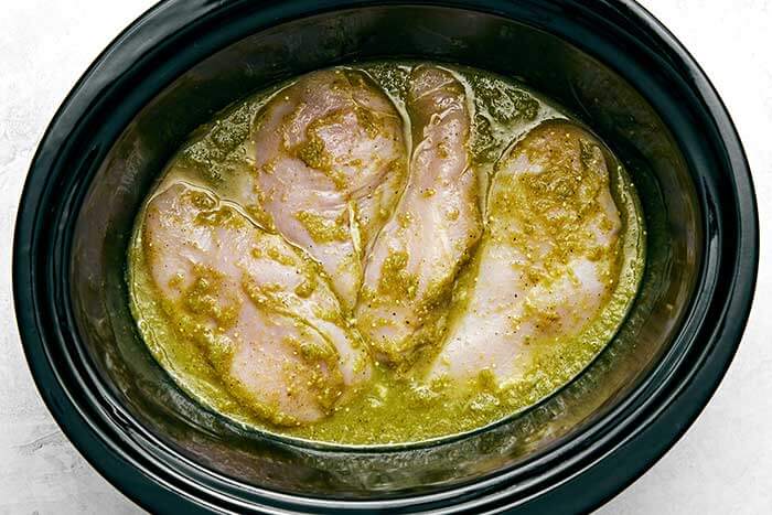Chicken breasts with salsa verde sauce in a slow cooker.