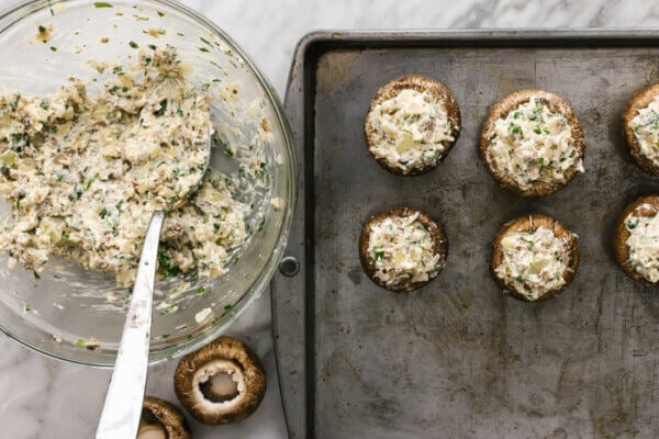 Stuffing mushrooms on a metal sheet pan.