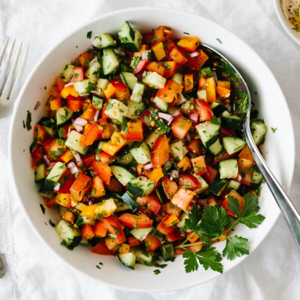 Israeli salad made from tomatoes, cucumber, bell pepper, red onion and herbs in a white bowl.