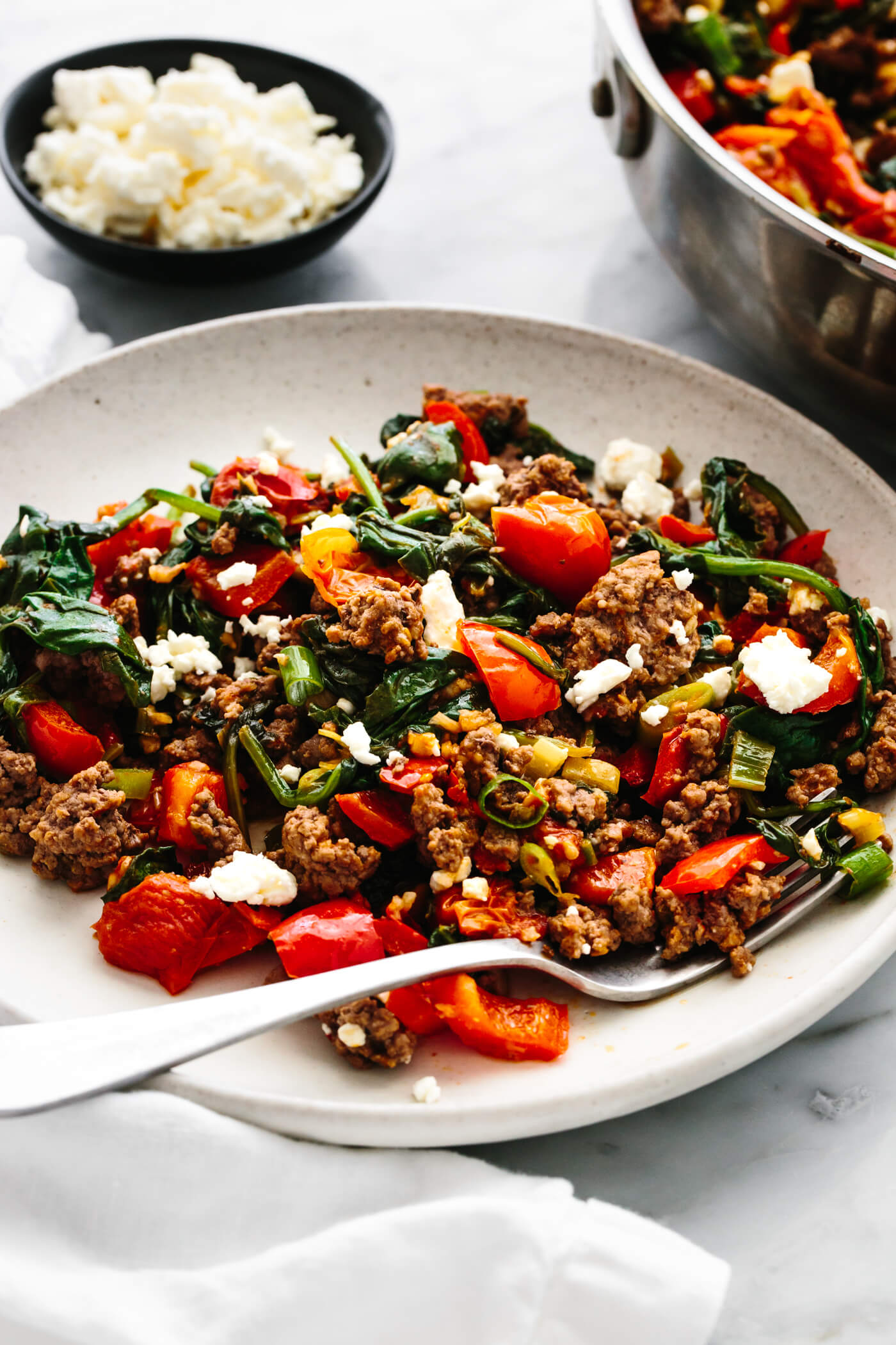 A plate of Mediterranean ground beef stir fry next to a bowl of feta.