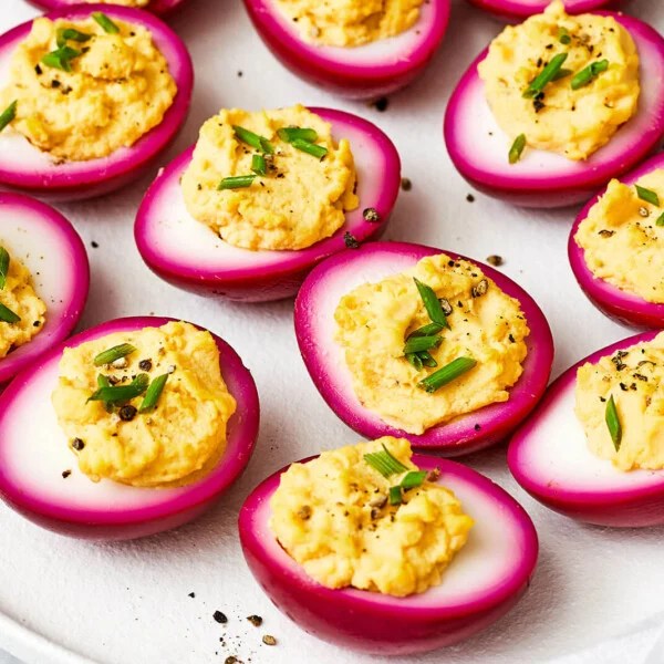 A white plate of beet pickled deviled eggs