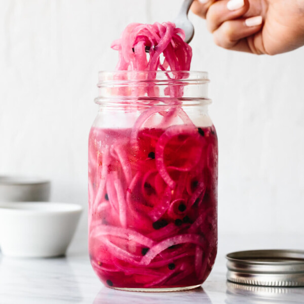 A mason jar of pickled red onions next to a lid
