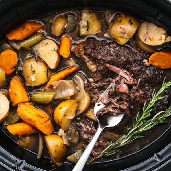 A slow cooker with pot roast in it