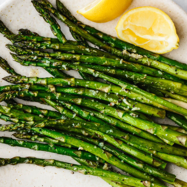 A white plate with roasted asparagus on top