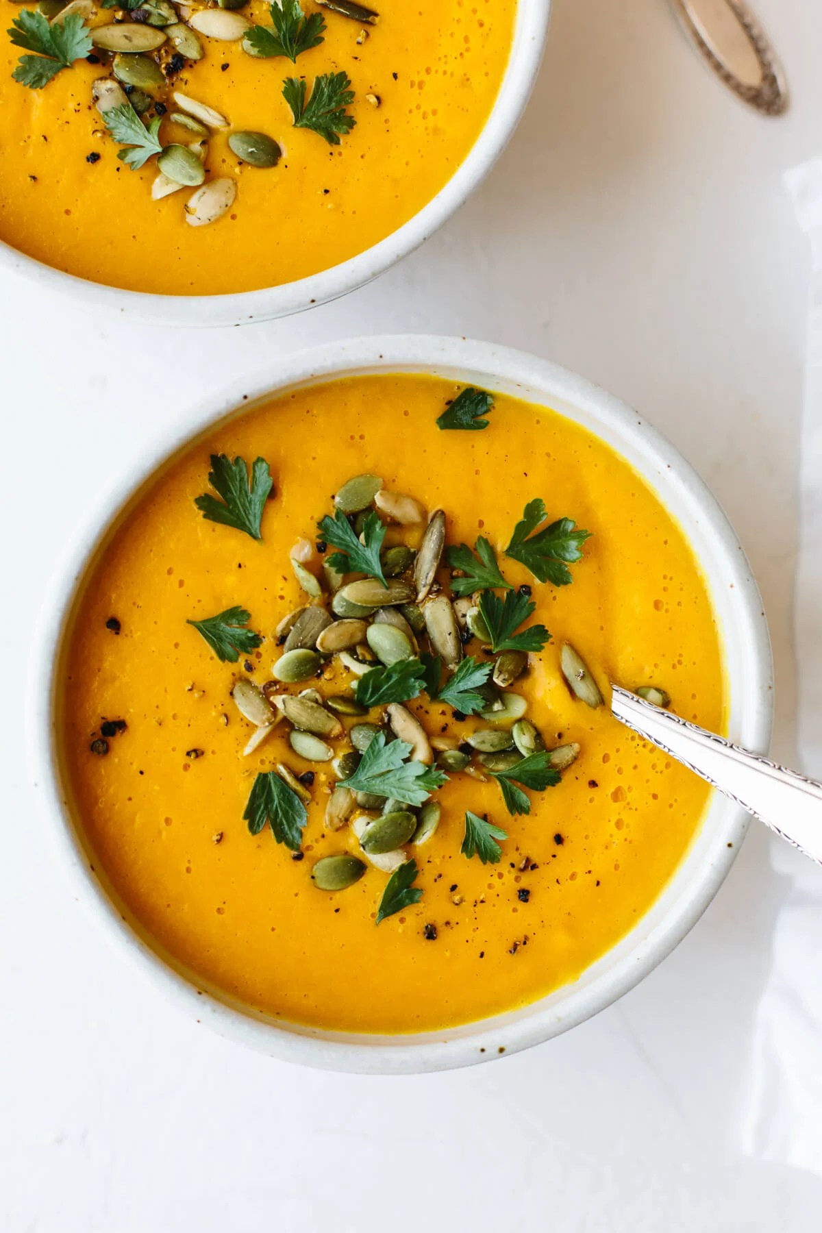 Two bowls of butternut squash soup with spoons.