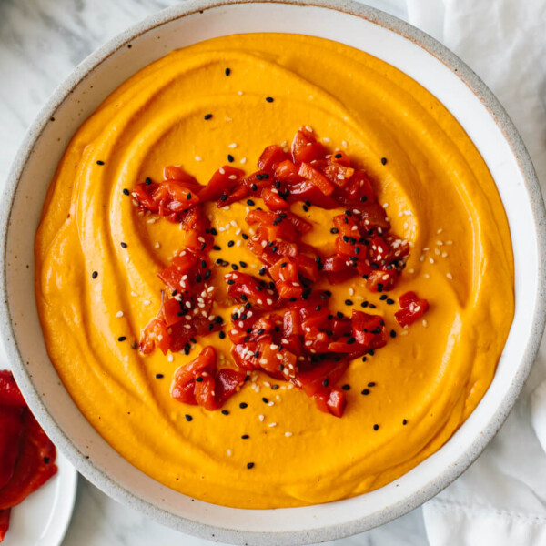 Roasted red pepper hummus next to peppers.