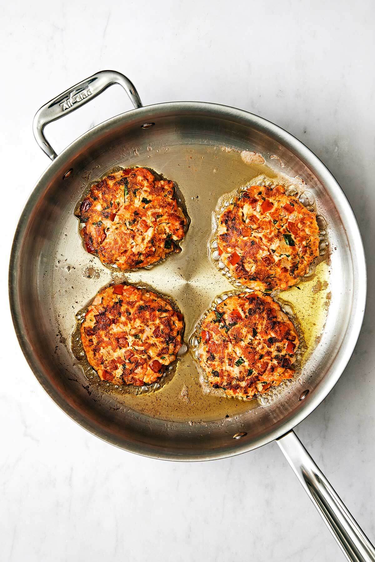 Cooking salmon patties in a pan with oil.