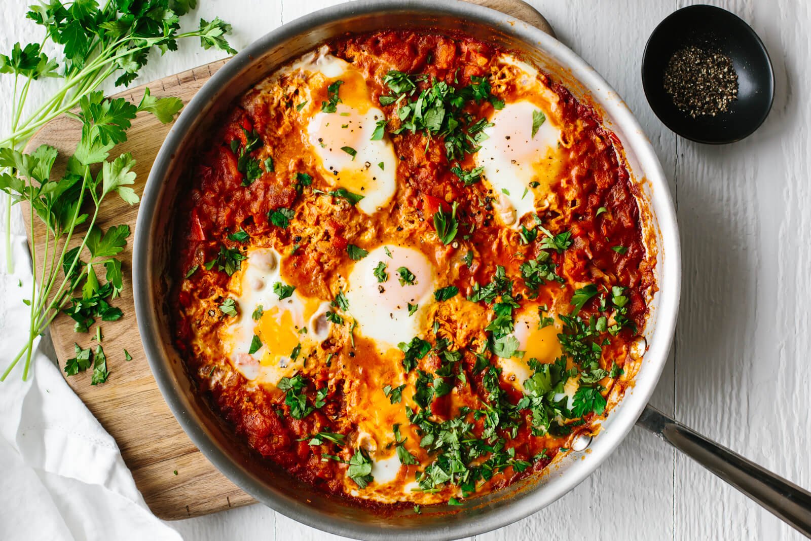 Shakshuka in a pan with fresh herbs on top.