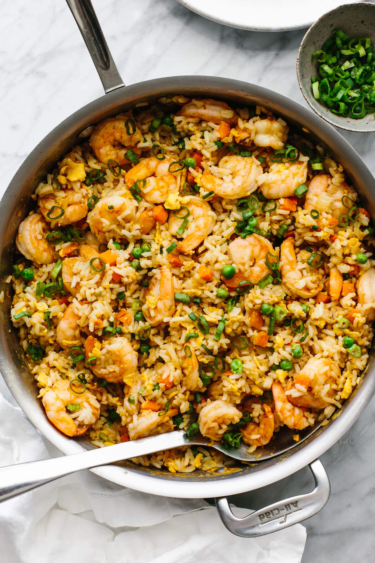 A pan with shrimp fried rice with a serving spoon.